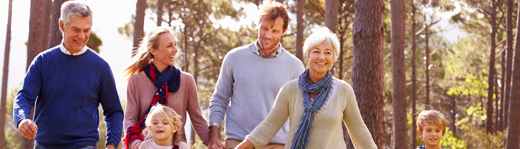 3 generations of a happy family walking through woods.